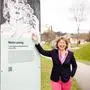 Rotraud Jungbauer auf der „Galerie der Gedanken“ entlang der Moosburger Schlosswiese vor einer Maria Lassnig-Zeichnung von Harald Schreiber