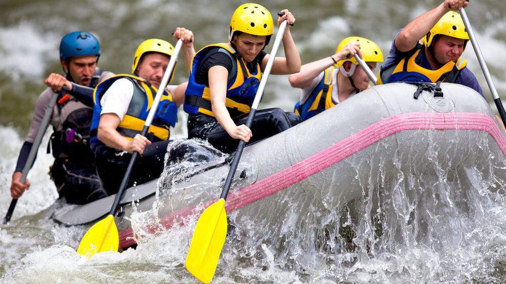 Group of people paddling while whitewater rafting