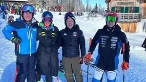 Vier Menschen in Skianzügen stehen im Schnee, der Himmel ist wolkenlos und sie lachen dabei in die Kamera | Begeisterung auf der Petzen