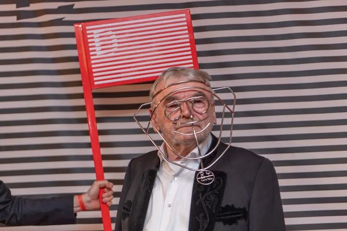 Er erhielt ein Kunstwerk, das von Constantin Luser gestaltet war. Eine variable Maske aus Draht, die der Charakterdarsteller hinter der Bühne sogleich zu einigen Posen hervorrief