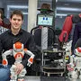 Baxter, der Roboter mit Hut und Schlips, umschlingt seine Erzeuger Markus Plass, Stefan Imlauer, Julia Nitsch und Emilian Jungwirth (v.l.). Er hat ein Lächeln im Gesicht und freut sich auf seinen ersten Auftritt am Freitag im Congress.