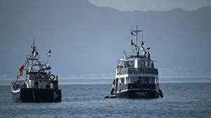 (FILES) A ship (R), known as the "Family" and is part of the Global Sumud Flotilla, is anchored off the coast of the village of Sidi Bou Said on September 9, 2025. Activists aboard a Gaza-bound aid flotilla said Israeli warships surrounded several of its boats on Wednesday and that the interception of the main vessels was under way. "The warships are moving in to intercept the flotilla -- only 81 nautical miles remain to Gaza," said the Maghreb contingent of the Global Sumud Flotilla in a statement. French politician Marie Mesmeur and Franco-Palestinian MEP Rima Hassan also reported that their boats were being intercepted. (Photo by FETHI BELAID / AFP)