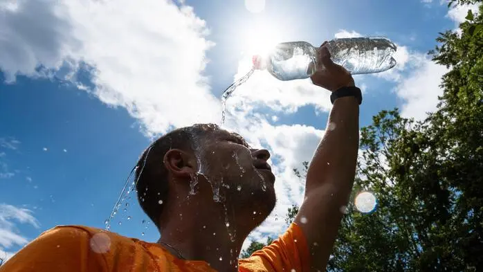 Ein Mann schüttet sich aufgrund der Hitze eine Flasche Wasser übers Gesicht