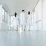 Three doctors walking down a corridor in hospital seen from behind
