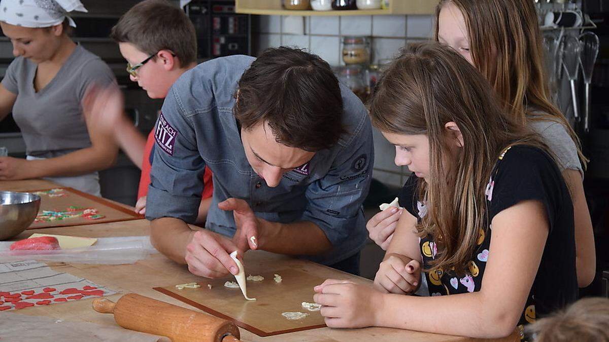 Juniorchef Dominik Fitz erklärt Katharina und Leonie die beste Technik für eine gelungene Hippe