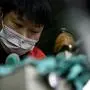 This photo taken on February 27, 2020 shows a worker wearing a face mask as he makes insoles at the Zhejiang Xuda Shoes Co. factory in Wenzhou. - The number of new cases of the COVID-19 coronavirus in China has declined in recent days, but infections in other countries have gathered pace. (Photo by NOEL CELIS / AFP)