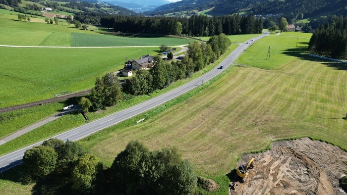 Zu sehen ist eine Straße, die sich durch Wiesen schlängelt
