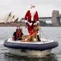 A man dressed as Santa Claus rides a boat with his dog in front of the Sydney Opera House, as part of Christmas Day celebrations for the annual Sydney to Hobart yacht race on December 25, 2023. (Photo by DAVID GRAY / AFP)