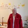 Eine alte Dame mit weißen Haaren und einer roten Jacke 