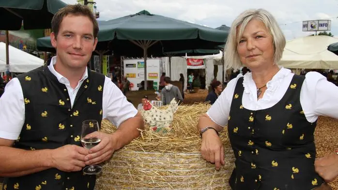Mutter und Sohn lehnen an einem Strohballen und lachen in die Kamera