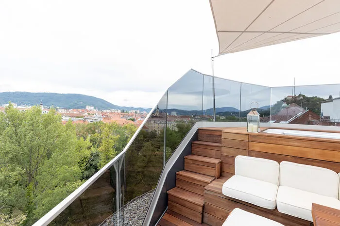 Überall auf der Terrasse befinden sich versteckte Laden und Fächer als Stauraum. Ein Sonnensegel sorgt für angenehmen Schatten. Ein Schwimm-Spa mit Gegenstromanlage kann sommers wie winter genutzt werden.