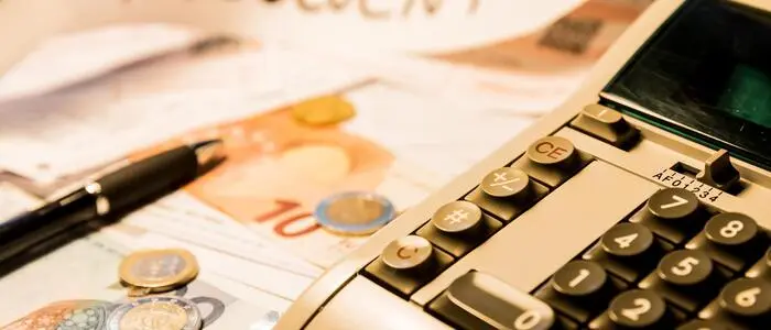 Vor einem Blatt mit der Aufschrift „insolvent“ liegt Geld und ein Rechner