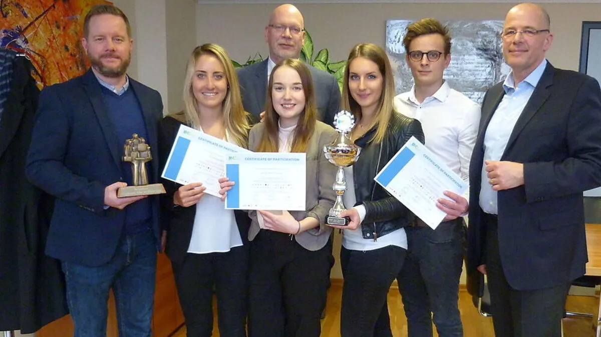 Geschäftsführer Michael Heritsch (im Hintergrund) und Institutsleiter Michael Mair (ganz rechts) gratulieren dem Studierendenteam und Coach Andrew Pullen (ganz links)