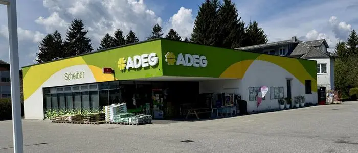 Ein seitlicher Blick auf ein Adeg-Geschäft mit grünem Logo um das gesamte Gebäude