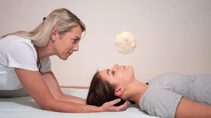 Eine Frau mit blonden Haaren hält eine Patientin am Kopf 
