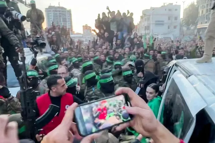 This screen grab taken from AFPTV shows one of the Israeli hostages exiting a vehicle to be handed over to the International Committee of the Red Cross (ICRC) during the hostage-prisoner exchange operation in Saraya Square in western Gaza City on January 19, 2025. The Israeli military said the Red Cross had confirmed the handover of three hostages on January 19, the first to be released as part of a ceasefire deal with Hamas. The Hostage and Missing Families Forum campaign group had identified the three women set to be released as Emily Damari, Romi Gonen and Doron Steinbrecher, seized during Hamas's October 7, 2023 attack that triggered the war. (Photo by AFPTV / AFP)