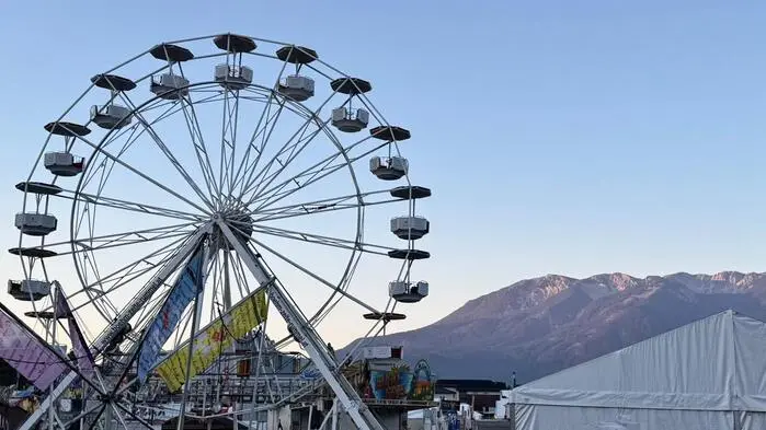 Ein Riesenrad, dahinter die Berge und Sonnenaufgang