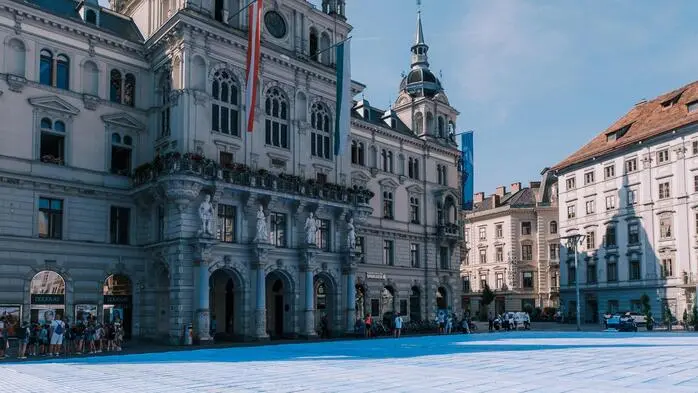 Auf dem Boden vor dem Grazer Rathaus am Hauptplatz sind unzählige blaue falsche Scheine geklebt.