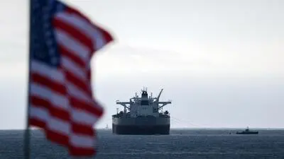 Eine US-Flagge im Vordergrund und ein Öltanker dahinter.