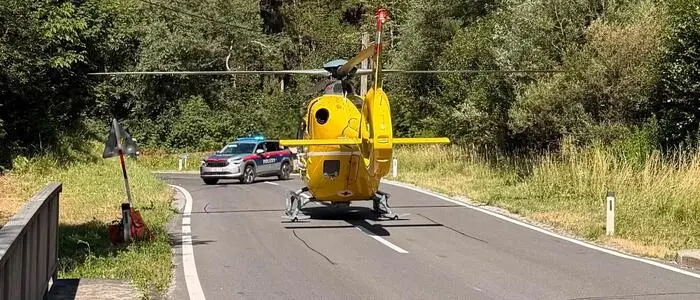 Bild zeigt einen gelben Hubschrauber, der auf der Straße gelandet ist, dahinter sperrt ein Polizeiauto die Straße ab
