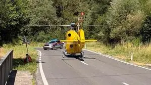 Bild zeigt einen gelben Hubschrauber, der auf der Straße gelandet ist, dahinter sperrt ein Polizeiauto die Straße ab