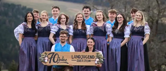 Eine Gruppe junger Erwachsener in Tracht posiert in der Natur