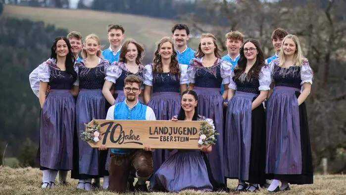 Eine Gruppe junger Erwachsener in Tracht posiert in der Natur