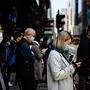 Pedestrians wear face masks, as a preventative measure against the COVID-19 coronavirus, as they walk on a footbridge in Hong Kong on February 12, 2020. - The virus, officially named COVID-19, has spooked markets around the world, having killed more than 1,100 people and infected tens of thousands since it emerged in central China at the end of last year. (Photo by Anthony WALLACE / AFP)