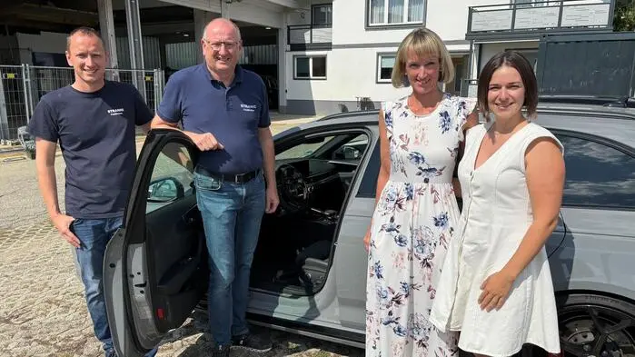 Zwei Männer und zwei Frauen unterschiedlichen Alters stehen vor einem Audi RS4.