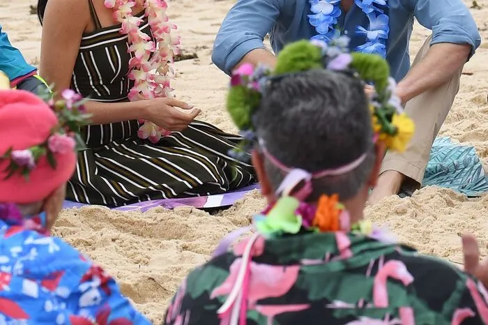 Das Blumenketten tragende Paar traf am Freitagmorgen Surfer und setzte sich mit Vertretern der Gruppe OneWave in den Sand.