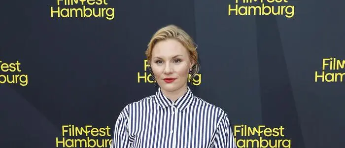 Rosalie Thomass in einer gestreiften Bluse und einem schwarzen Rock am Red Carpet des Filmfest Hamburg.