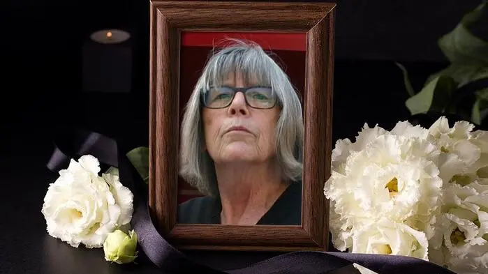 Ein Foto von einer Frau in einem Bilderrahmen, daneben liegen weiße Blumen