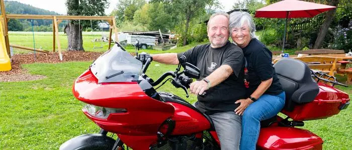 Ein Mann und eine Frau sitzen auf einem roten Motorrad und lächeln für die Kamera