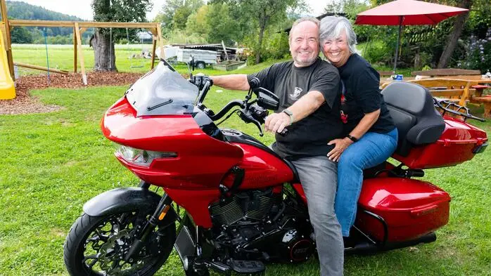Ein Mann und eine Frau sitzen auf einem roten Motorrad und lächeln für die Kamera