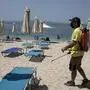 A man disinfects sun beds at a beach in the Alimos suburb, southwest of Athens, Saturday, May 8, 2021. Beaches run by a private concession reopened Saturday, a week ahead of the official launch of the tourism season. (AP Photo/Yorgos Karahalis)