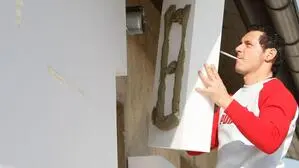 Ein Arbeiter klebt eine Wärmedämmungsplatte an die Außenfassade eines Wohnhauses