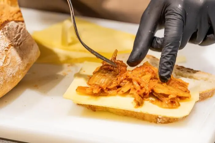 Kimchi wird großzügig auf den Käse verteilt.