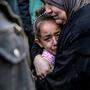 Eine palästinensische Frau hält ein Kind im Arm, während sie vor der Leichenhalle des Al-Shifa-Krankenhauses in Gaza um ihre bei israelischem Bombardement getöteten Angehörigen trauert.