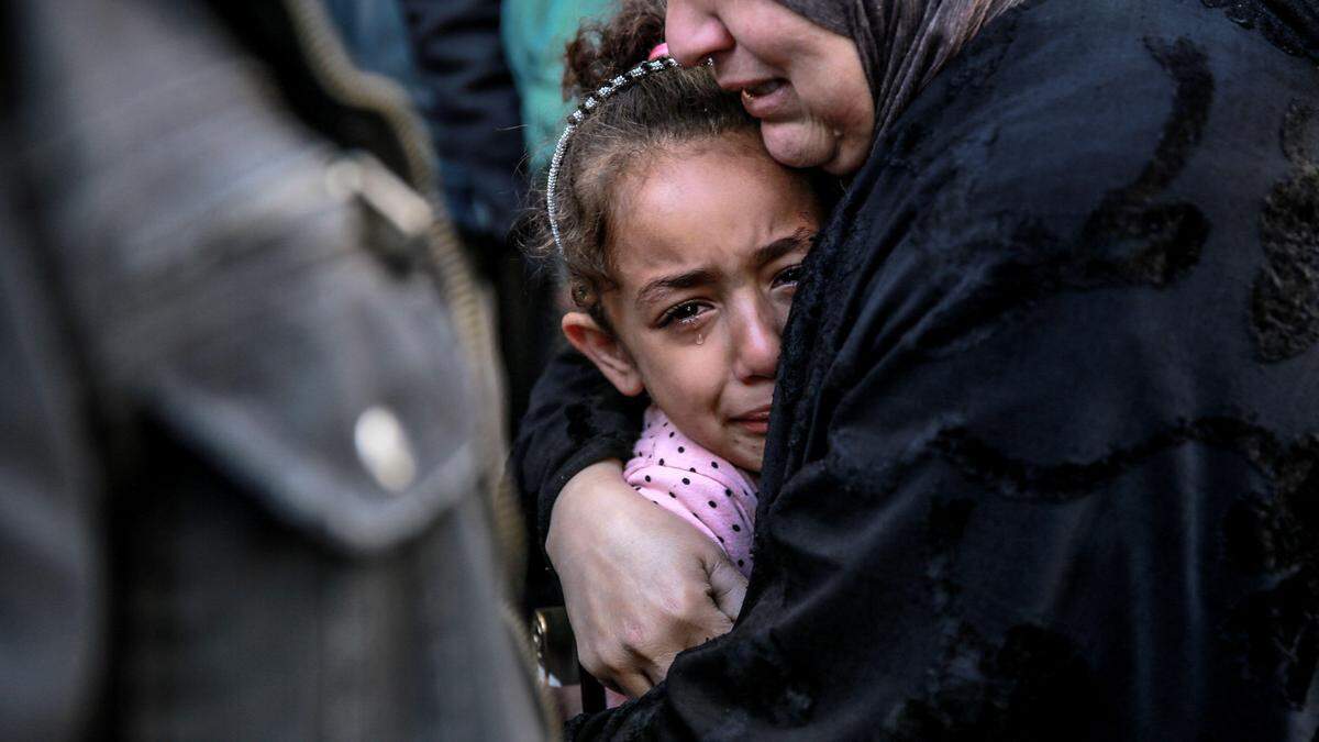 Eine palästinensische Frau hält ein Kind im Arm, während sie vor der Leichenhalle des Al-Shifa-Krankenhauses in Gaza um ihre bei israelischem Bombardement getöteten Angehörigen trauert.