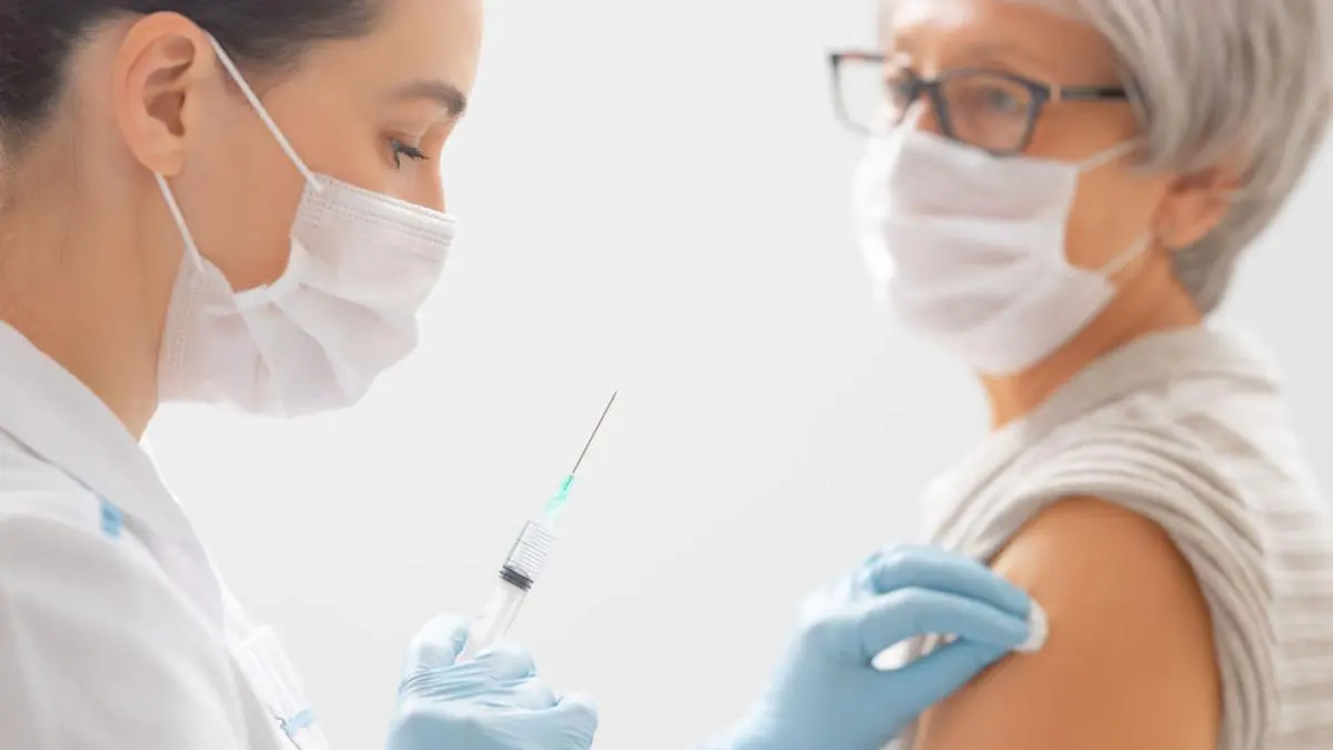 Doctor giving a senior woman a vaccination. Virus protection. COVID-2019.