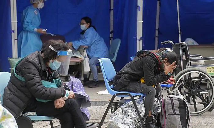 People, including current hospital patients, showing COVID-19 symptoms wait at a temporary holding area outside Caritas Medical Centre in Hong Kong Wednesday, Feb. 16, 2022. China's leader Xi Jinping took a personal interest in Hong Kong's outbreak, saying it was the local government's 