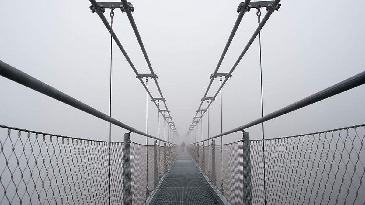 Im dichten Nebel überquert ein Unerschrockener die Seilhängebrücke  