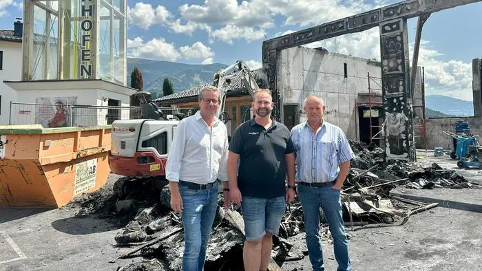 Drei Männer vor einer Brandruine