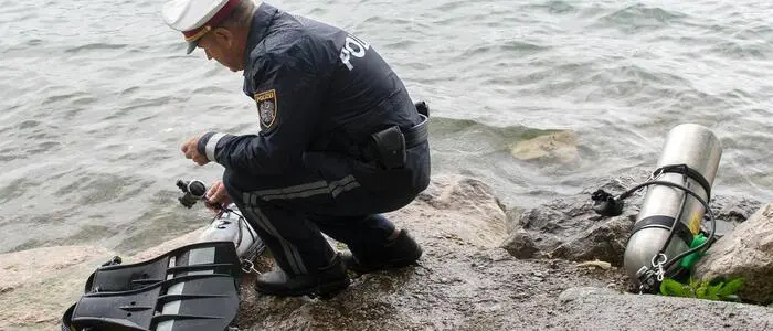 Archivbild: Ein Polizist begutachtet eine Tauchausrüstung am Ufer des Attersees