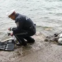 Archivbild: Ein Polizist begutachtet eine Tauchausrüstung am Ufer des Attersees