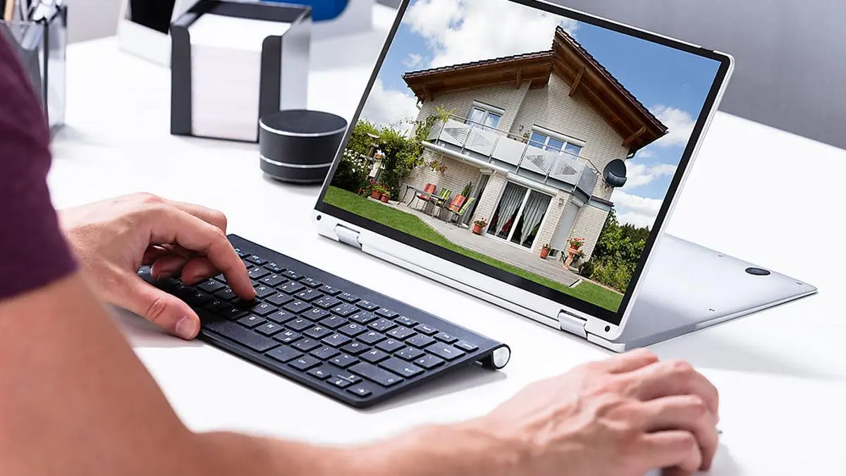 Man Selecting New House On Laptop At Home