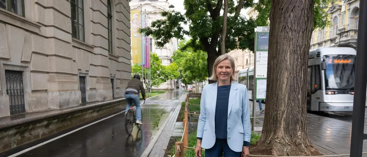 Judith Schwentner steht in der Neutorgasse, links der neue Radweg, rechts kommt die Straßenbahn, hinter Bäume und Beete