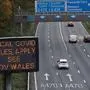 (FILES) In this file photo taken on October 17, 2020 Traffic passes a COVID-19 sign displayed along the Cardiff-bound M4 motorway near Newport, in southeast Wales, as further restrictions come into force as the number of novel coronavirus COVID-19 cases rises. - Wales will impose a full "firebreak" lockdown for two weeks from October 23, to try to reduce a soaring number of new coronavirus cases, First Minister Mark Drakeford said on October 19, 2020. Under the new rules, everyone will be required to stay at home with only critical workers expected to go to their workplaces. (Photo by Geoff Caddick / AFP)