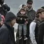 Refugees and migrants who arrived on Lesbos island after March 1, stand in the port of Mytilene next to the military carrier which accomodates them on the island of Lesbos on March 7, 2020. - Over 1,700 migrants have landed on Lesbos and four other Aegean islands from Turkey over the past week, adding to the 38,000 already crammed into abysmal and overstretched refugee centres. (Photo by LOUISA GOULIAMAKI / AFP)
