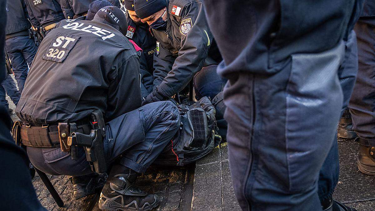 Der Festgenommene klagt, er habe Atemprobleme bekommen, weil er mit dem Hals auf der gehsteigkante arretiert worden sei.